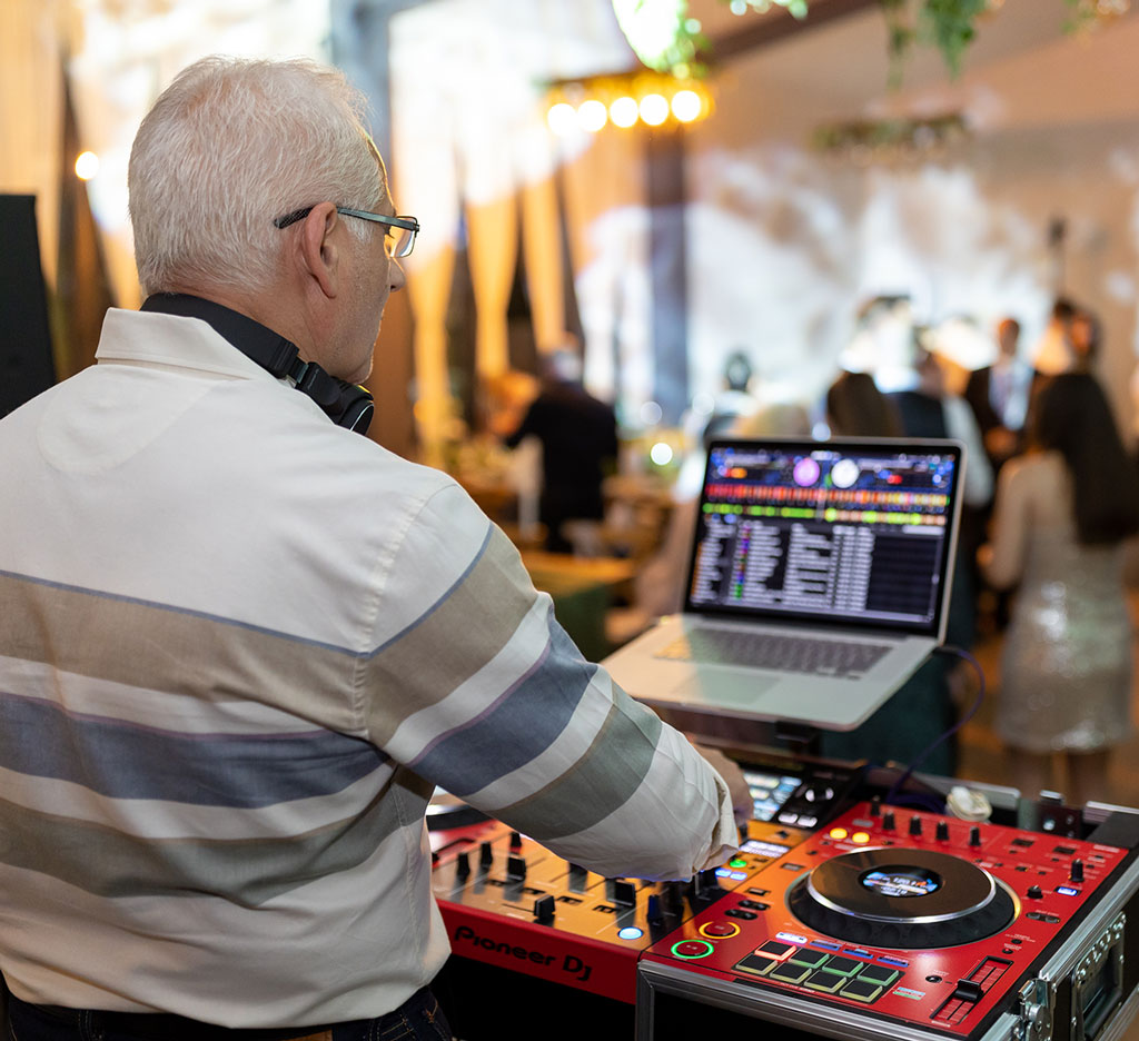 DJ de nunta fotografiat din spate, lucrand la pupitru DJ Pioneer