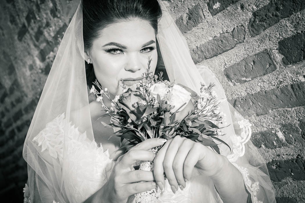 Fotografie portret detaliu cu mireasa tinand buchetul de flori in fata la sedinta foto de nunta