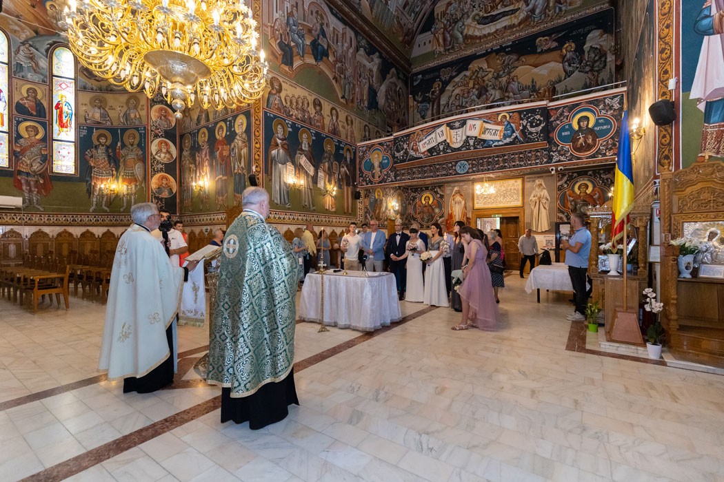 Cadru ultra wide surprins de fotograf in biserica la cununia religioasa, cu preotii, mirii, nasii si invitatii